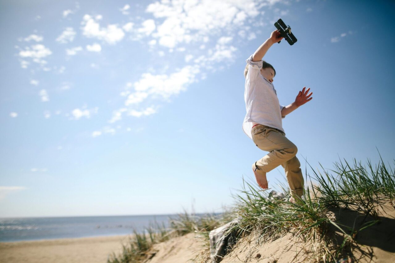 Child running on the beach with a toy plane