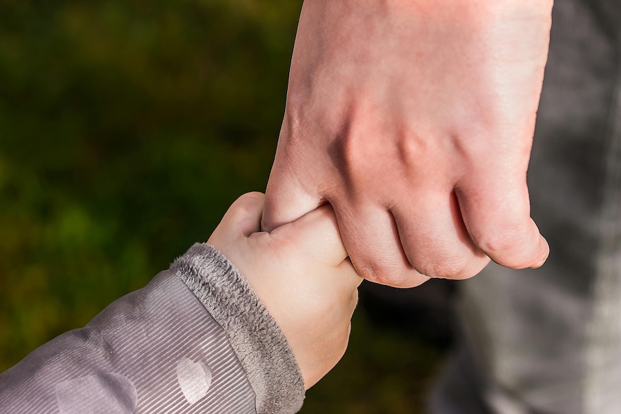 Child holding hands with an adult