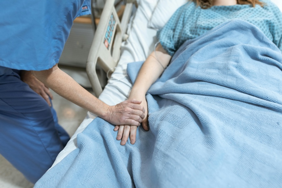 Picture of someone in hospital with another person holding their hand