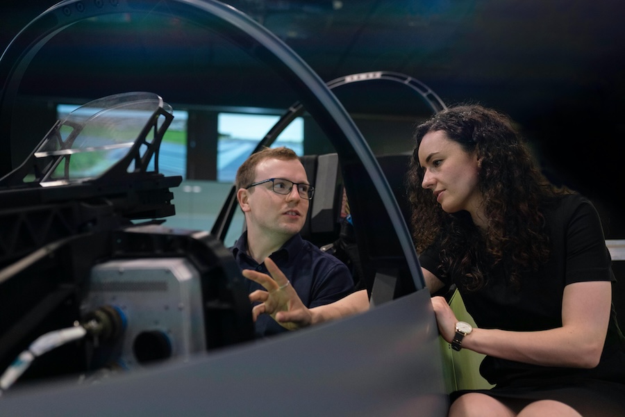 Image of someone in a flight simulator being spoken to by an instructor