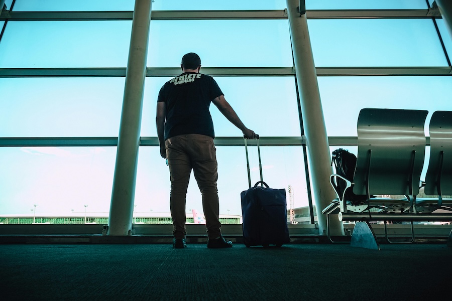 Man standing in an airport with a suitcase ready to fly