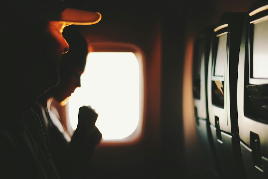 Image of a young woman looking out of a plane window during flight