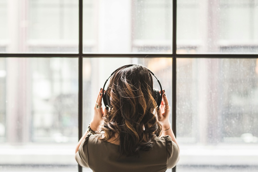 Image of the back of a young woman's head while she listens to music on headphones