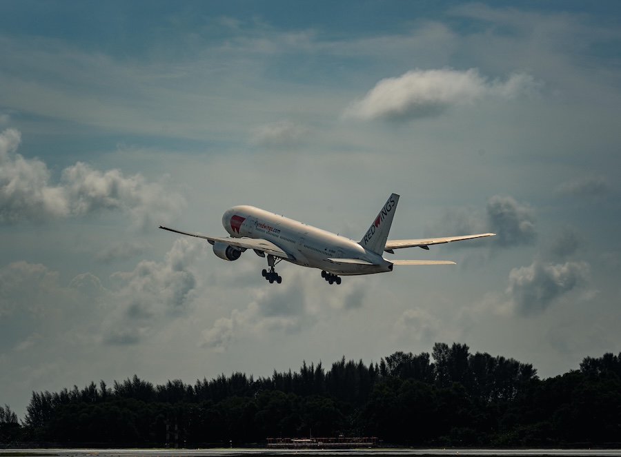 Image of a plane taking off into clouds on a bright day