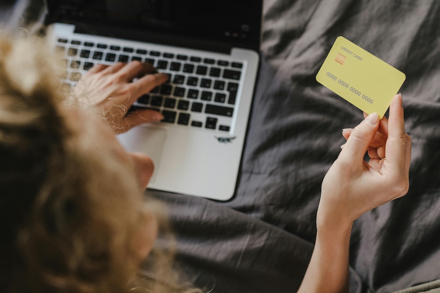 Image of a woman booking a holiday online using a fake gold credit card